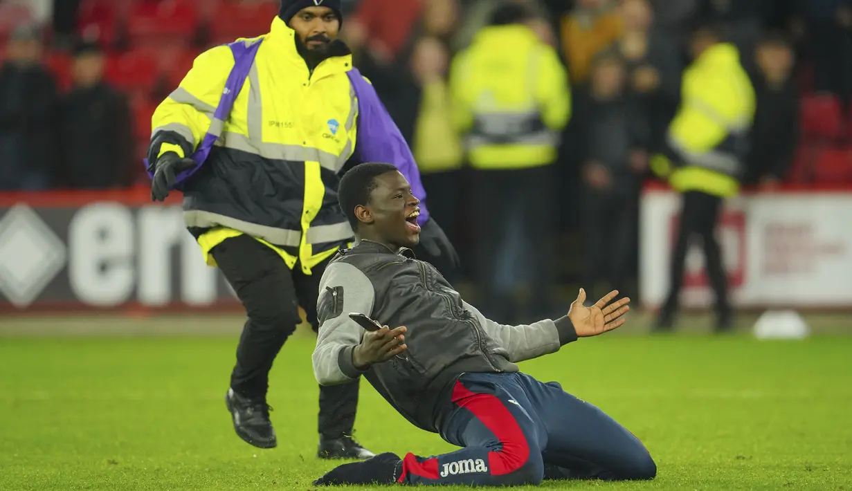 Seorang fans memasuki lapangan setelah berakhirnya laga pekan ke-9 Liga Inggris 2023/2024 antara Sfheffield United menghadapi Manchester United di Bramall Lane, Sheffield, Minggu (22/10/2023) dini hari WIB. (AP Photo/Jon Super)