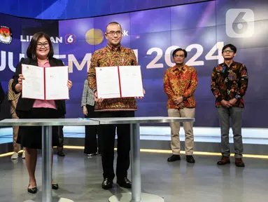 Ketua Komisi Pemilihan Umum (KPU) Hasyim Asy'ari (tengah kanan) bersama CFO KLY Octaviany Sarimawan (tengah kiri) menunjukkan dokumen kerja sama saat acara penandatanganan MoU antara Emtek dengan KPU di SCTV Tower, Jakarta, Selasa (30/8/2022). Kerja sama KPU dengan Emtek ini terkait sosialisasi Pemilihan Umum yang akan diselenggarakan 2024 mendatang. (Liputan6.com/Johan Tallo)