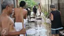 Warga bergotong royong membersihkan lumpur sisa banjir yang menutup jalan, Jakarta, Senin (7/11). Sebelumnya, ratusan rumah warga di RW 02 Cawang, Kramat Jati, Jakarta Timur tergenang akibat banjir kiriman dari kawasan Bogor. (Liputan6.com/Yoppy Renato)