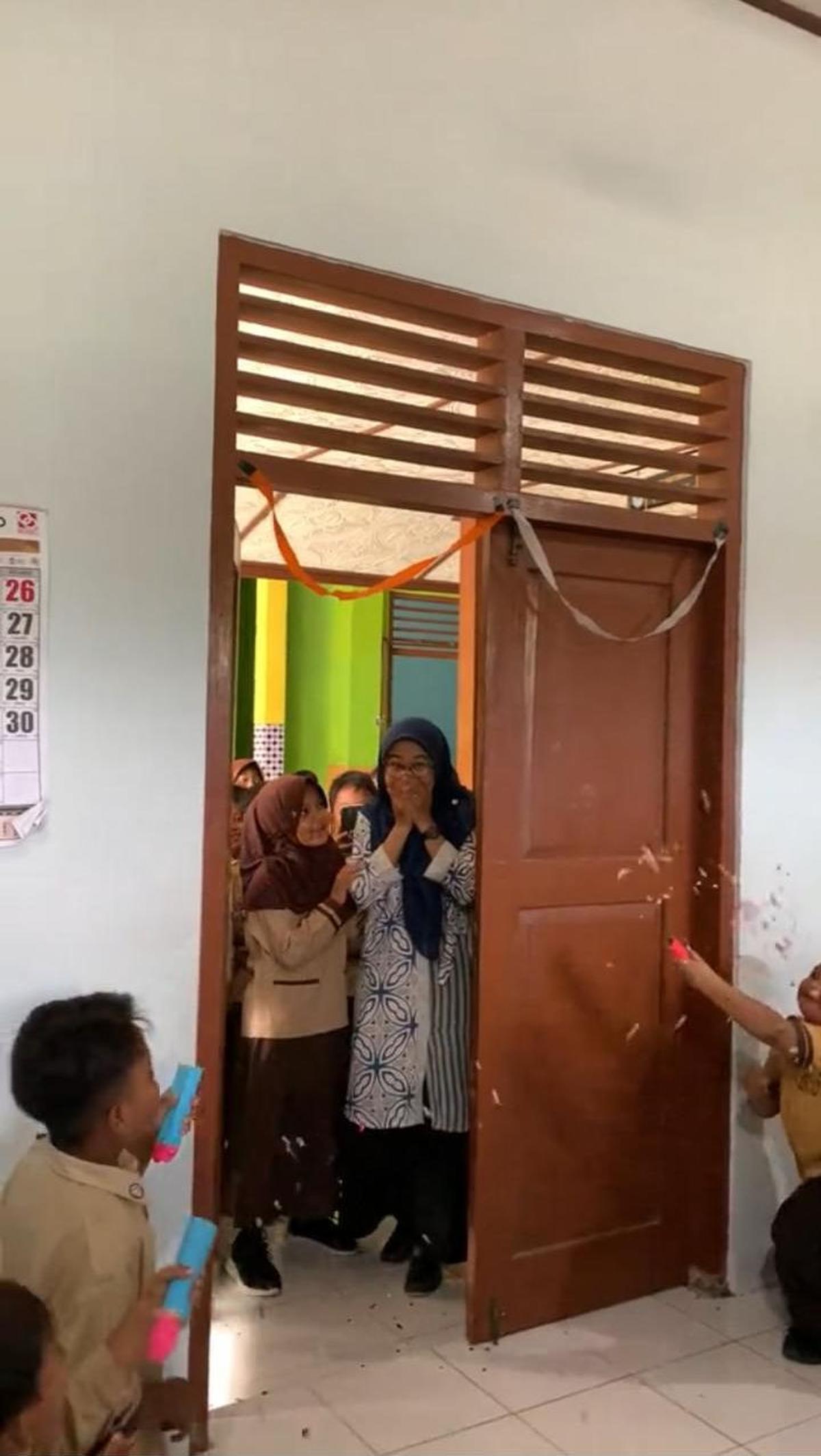 Saat pintu di buka dari luar oleh anak-anak perempuan, ibu guru ini pun tampak kaget Ia seolah tak menyangka akan dapat kejutan dari murid-muridnya.