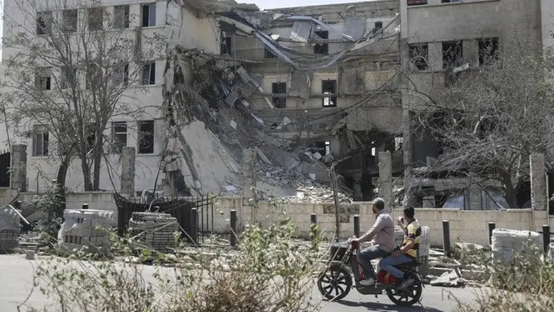 Orang-orang berjalan di depan gedung Kementerian Pertahanan Suriah di Damaskus yang rusak parah akibat serangan udara Israel pada Kamis (17/7/2025).