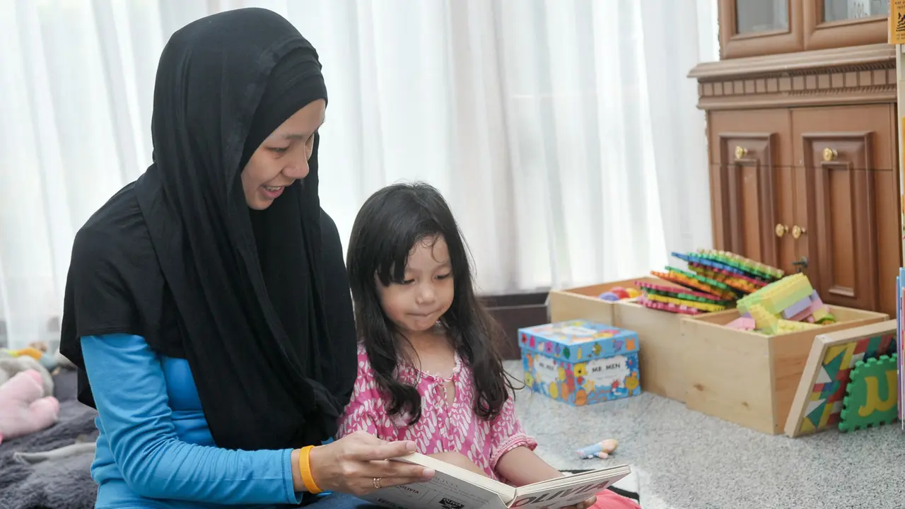 Seorang ibu membacakan sebuah buku dongen anak di ruang perpustakaan Rabbit Hole, Kemang, Jakarta, Selasa (11/10).