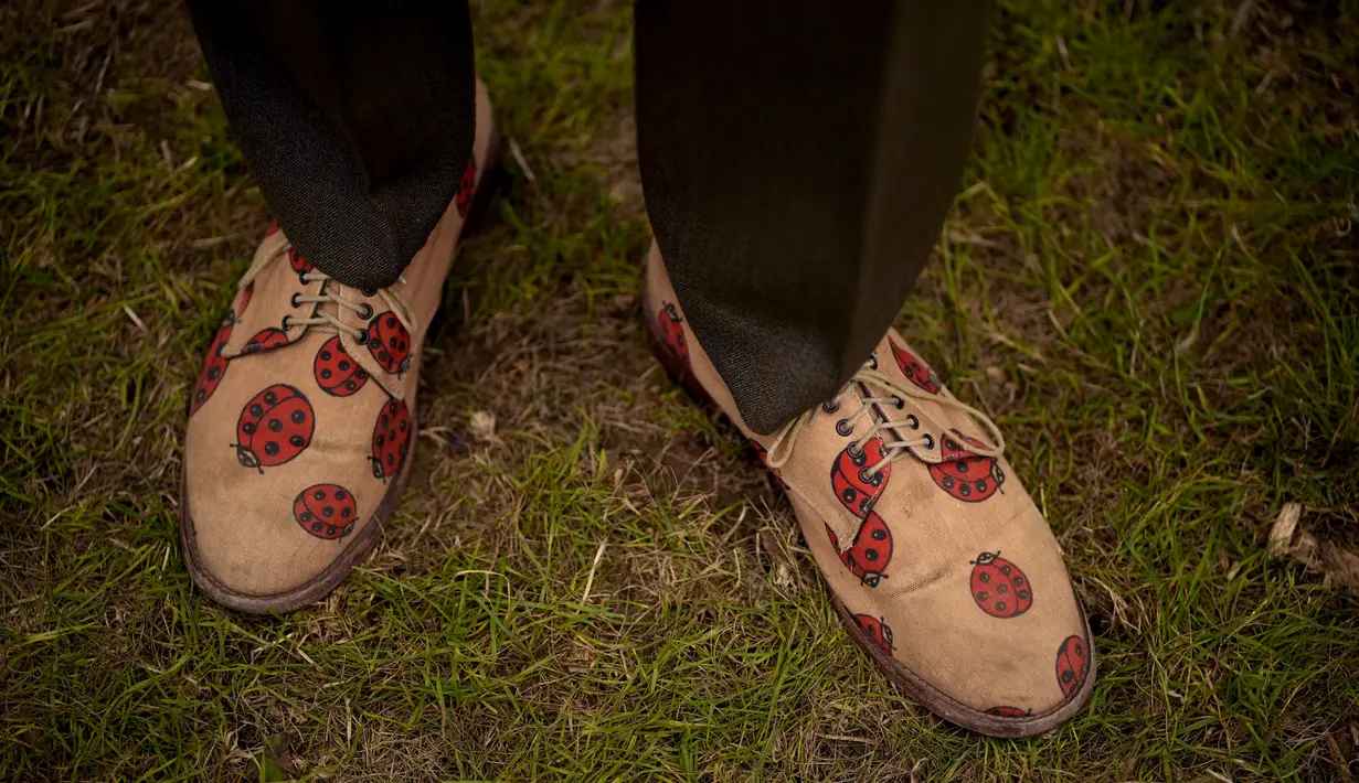 Seorang desainer pameran taman mengenakan sepatu dengan gambar kepik selama RHS Chelsea Flower Show 2021 di London pada Senin (20/9/2021). Pertunjukan bunga Chelsea sempat ditunda dari tanggal musim semi biasanya karena pembatasan penguncian di tengah pandemi COVID-19. (AP Photo/Matt Dunham)