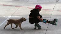 Seekor anjing berlari mengejar wanita muda yang sedang berlatih trik sepatu roda di Parque Mexico, Condesa, Mexico City, Meksiko, Sabtu (29/8/2020). Sejumlah warga tetap bersantai dan berolahraga di tengah pandemi virus corona COVID-19. (AP Photo/Rebecca Blackwell)