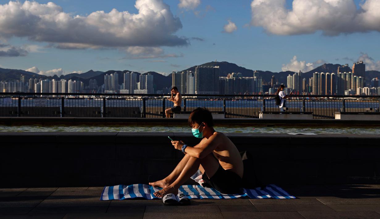 Seorang pria yang mengenakan masker duduk berjemur di sebuah taman di Hong Kong, Rabu (22/7/2020). Hong Kong menghadapi "tahap kritis" dalam perjuangannya melawan COVID-19, dan pemerintah sedang memperpanjang langkah-langkah baru untuk menjaga jarak sosial. (AP Photo/Kin Cheung)