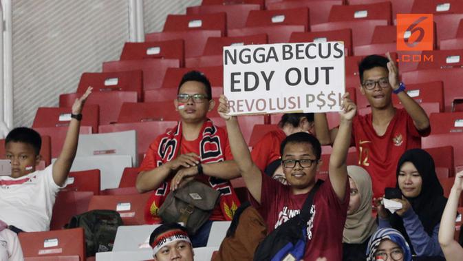 Suporter Timnas Indonesia memperlihatkan poster memprotes Ketum PSSI, Edy Rahmayadi, saat melawan Filipina pada laga Piala AFF 2018 di SUGBK, Jakarta, Minggu (25/11). Kedua negara bermain imbang 0-0. (Bola.com/M. Iqbal Ichsan)