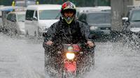 Pengendara sepeda motor menerjang genangan air akibat hujan lebat di Manila, Filipina, Kamis (27/7). Pihak Biro Cuaca setempat memberi peringatan agar warga terus berhati-hati beraktivitas di luar rumah selama musim penghujan. (AP/Bullit Marquez)