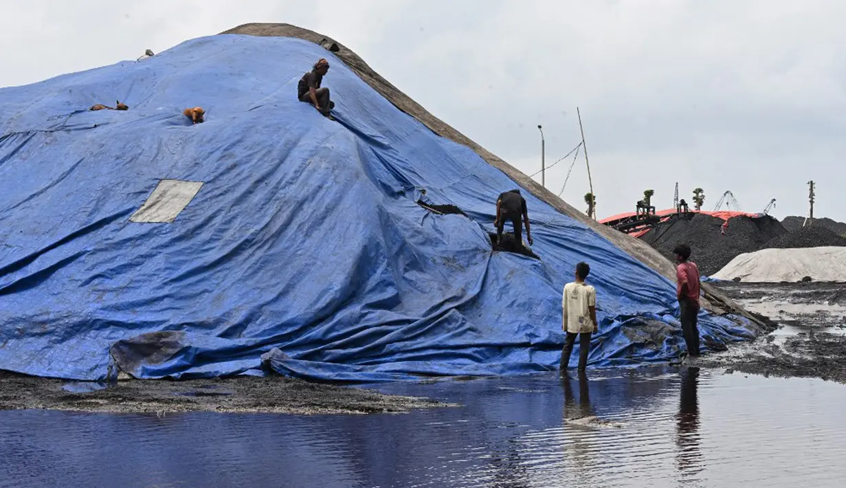 Pekerja menutupi tumpukan batu bara dengan terpal di Pelabuhan Marunda, Jakarta, 17 Januari 2022. Indonesia melonggarkan larangan ekspor batu bara. (ADEK BERRY/AFP)