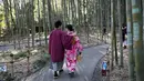 Wisatawan mengenakan kimono berjalan-jalan di Hutan Bambu Sagano di Arashiyama, Kyoto, Jepang pada 8 Desember 2018. Hutan seluas 16 km2 ini dinobatkan sebagai salah satu hutan terbaik di dunia. (Behrouz MEHRI / AFP)
