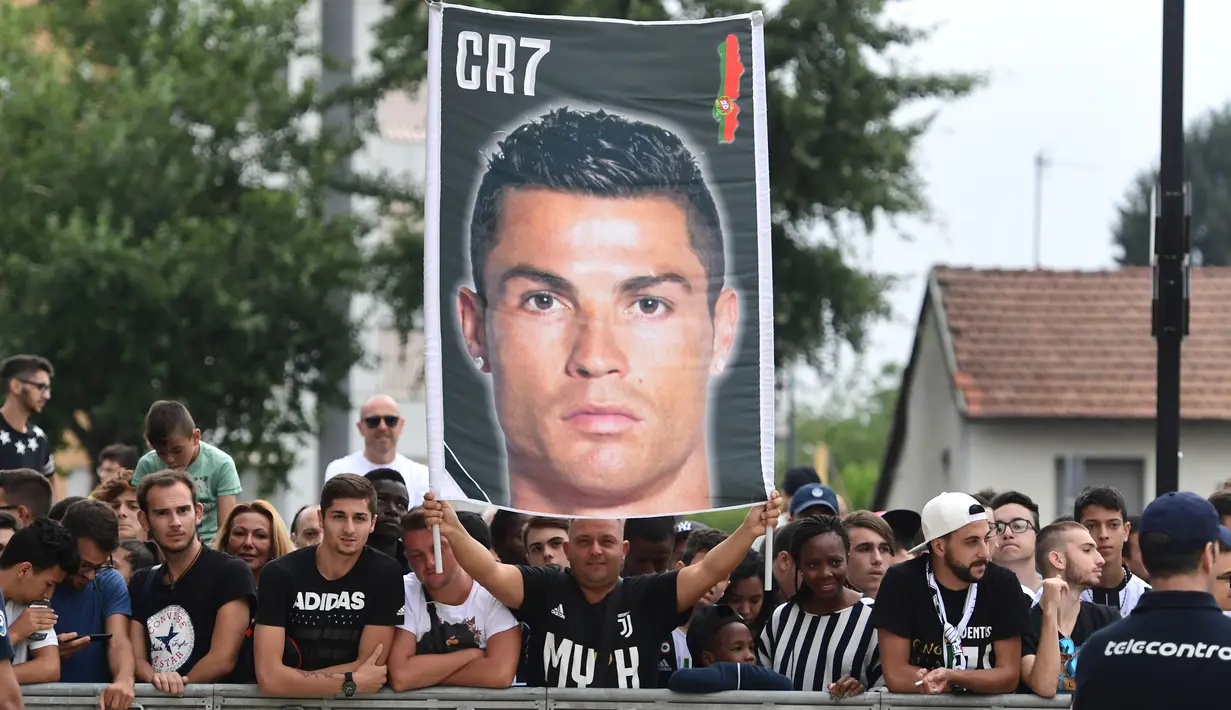 Suporter Juventus membawa spanduk saat menyambut kedatangan pemain baru Juventus Cristiano Ronaldo untuk menjalani tes medis di pusat layanan kesehatan Juventus (J-Medical) di Turin, Italia, (16/7). (AFP Photo/Miguel Medina)