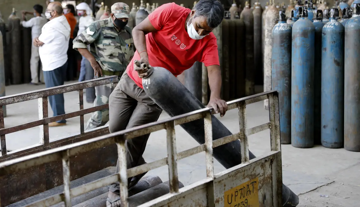 Pekerja memuat tabung oksigen di stasiun pengisian di pinggiran Prayagraj, India, pada 23 April 2021. Otoritas India bergegas membawa tangki oksigen ke rumah sakit tempat pasien COVID-19 tercekik di tengah gelombang virus corona terburuk di dunia. (AP Photo/Rajesh Kumar Singh)