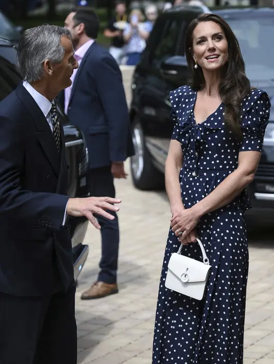 Kate Middleton melengkapinya dengan tas crossbody putih kecil dari Mulberry dan anting-anting mutiara dari Shyla London. (Daniel Leal/Pool via AP)