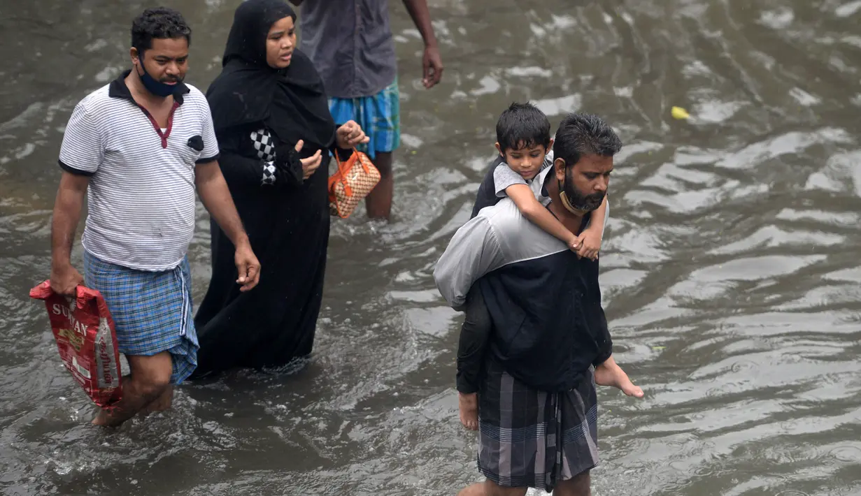 Orang-orang mengarungi jalan yang banjir setelah hujan lebat di Chennai, India (8/11/2021). Chennai dilanda Curah Hujan Terberat Sejak 2015,  Pihak berwenang Keluarkan Peringatan Banjir. (AFP/Arun Sankar)