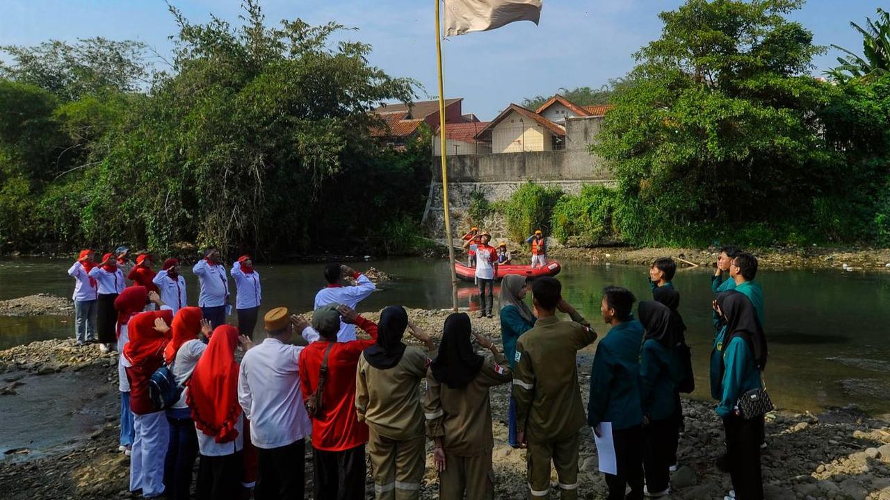 Para warga Kambung Kedung Halang yang berpartisipasi terlihat melakukan hormat saat mengikuti upacara pengibaran bendera di Sungai Ciliwung yang keadaan airnya hampir mengering.