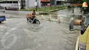 Lantaran nekat menerjang genangan air, pengendara sepeda motor terpaksa menuntun kendaraannya karena mogok (Liputan6.com/Andrian M Tunay)