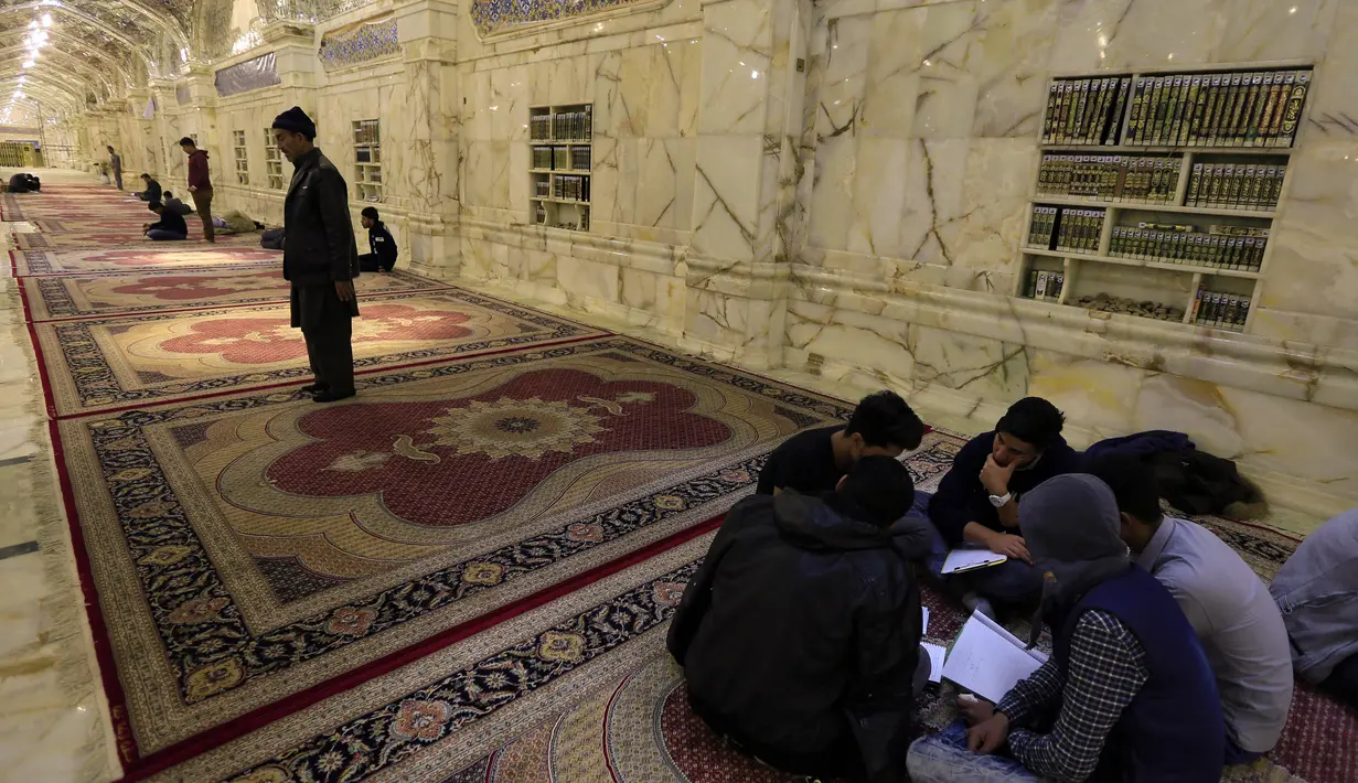 Sejumlah orang berdoa dan salat di dalam masjid Imam Ali di kota Najaf, Irak (23/1). Kompleks pemakaman Ali Bin Abi Thalib atau Imam Ali ini adalah pemakaman terbesar di dunia, pemakaman ini meliputi 1.485,5 hektar. (AFP Photo/Haidar Hamdani)