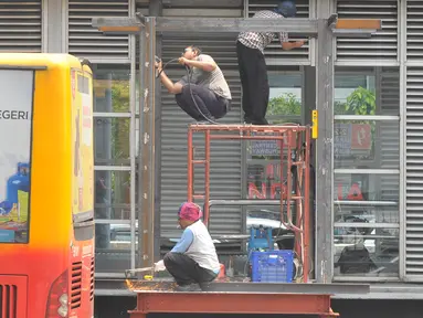 Pekerja merenovasi halte Busway Harmoni, Jakarta, Jum'at (29/1/2016). Perbaikan dilakukan pada jalur masuk penumpang karena sempat ambruk beberapa waktu lalu. (Liputan6.com/Faisal R Syam)