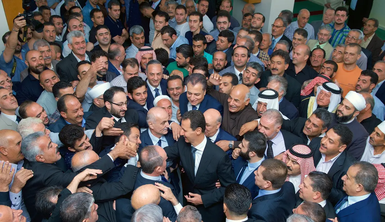 Presiden Suriah, Bashar al-Assad bersalaman dengan para pendukungnya usai melaksanakan salat Idul Adha di Masjid Agung Qara, di wilayah Qalamoun di pinggiran ibukota Suriah Damaskus (1/9). (AFP Photo/Sana/Handout)