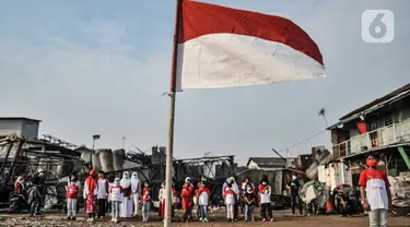 Anak-anak Kelas Jurnalis Cilik (KJC) saat menggelar upacara memperingati Hari Kemerdekaan ke-76 Republik Indonesia di Cilincing, Jakarta, Selasa (17/8/2021). Upacara peringatan HUT ke-76 RI yang digelar di kawasan pesisir tersebut berlangsung khidmat. (merdeka.com/Iqbal S. Nugroho)