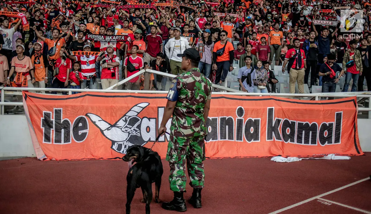 Personel TNI membawa anjing saat melihat pagar pembatas tribun penonton yang rusak saat pertandingan Shoppe Liga 1 antara Persija dengan Persib di SUGBK, Jakarta,  Rabu (10/7/2019). Suporter sepak bola merusak pagar pembatas usai berakhirnya laga Persija kontra Persib. (Liputan6.com/Faizal Fanani)