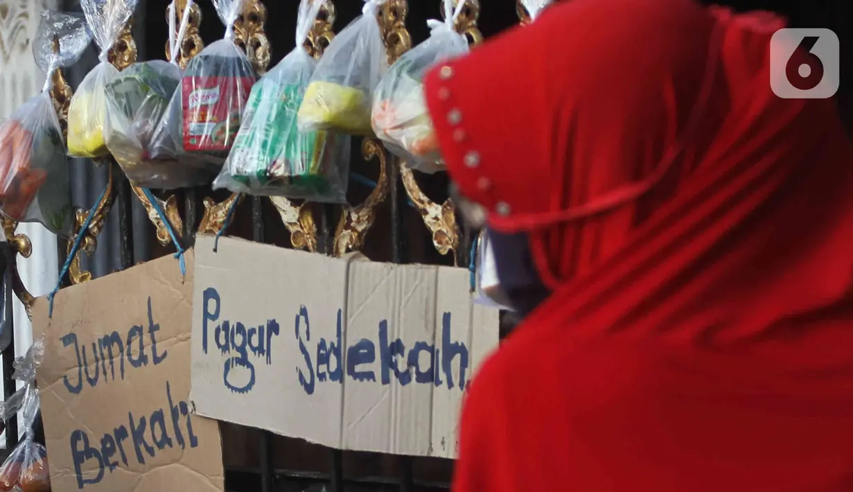 Sejumlah sayuran, beras, dan bumbu masak secara gratis yang digantung pada pagar rumah di Gang Palautan, Cilodong, Depok, Jumat (21/1/2022). Warga Rt 04 Rw 01 di kawasan tersebut secara swadaya berbagi setiap hari Jumat kepada warga yang terdampak pandemi COVID-19. (Liputan6.com/Herman Zakharia)