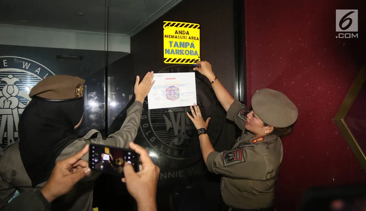 Petugas Satpol PP wanita memasang surat segel di Sense Karaoke di Mangga Dua Square, Jakarta, Kamis (19/4). Dari penggerebekan itu, BNN menemukan adanya peredaran narkoba di Sense Karaoke. (Liputan6.com/Arya Manggala)