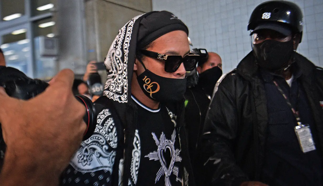 Mantan pemain timnas Brasil, Ronaldinho tiba di bandara El Galeao di Rio de Janeiro, setelah menjalani tahanan rumah di Paraguay, Selasa (25/8/2020). Ronaldinho menghirup udara bebas setelah lima bulan menjadi tahanan rumah karena memasuki Paraguay dengan paspor palsu. (Carl DE SOUZA/AFP)