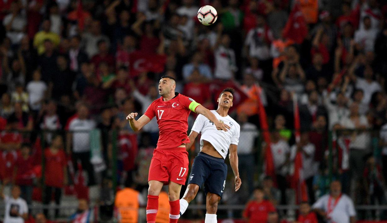 Striker Turki, Burak Yilmaz, duel udara dengan bek Prancis, Raphael Varane, pada laga kualifikasi Piala Eropa 2020 di Stadion Buyuksehir Belediyesi, Minggu (9/6). Turki menang 2-0 atas Prancis. (AFP/Bulent Kilic)