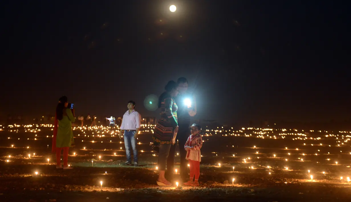 Warga India mengabadikan gambar di Sangam saat festival 'Dev Deepawali,' atau festival cahaya, di Allahabad, Rabu (25/11).  Festival ini adalah perayaan atas kemenangan kebaikan atas kejahatan. (AFP PHOTO/Sanjay Kanojia)