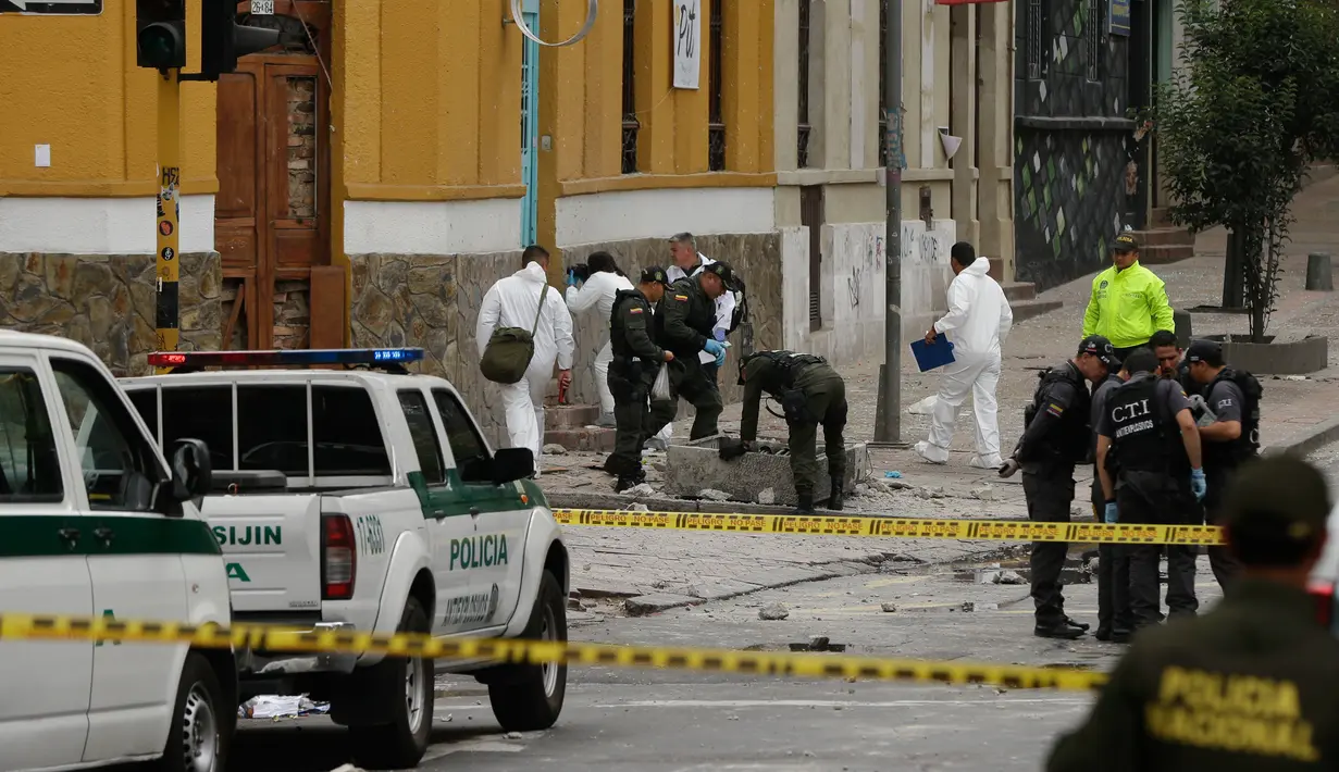 Polisi Kolombia dan ahli forensik memeriksa lokasi ledakan di dekat arena adu banteng Plaza Santamaria di pusat kota Bogota, Minggu (19/2). Sebagian besar korban adalah polisi yang tengah bertugas untuk mengamankan demonstrasi. (AP Photo/Ricardo Mazalan)