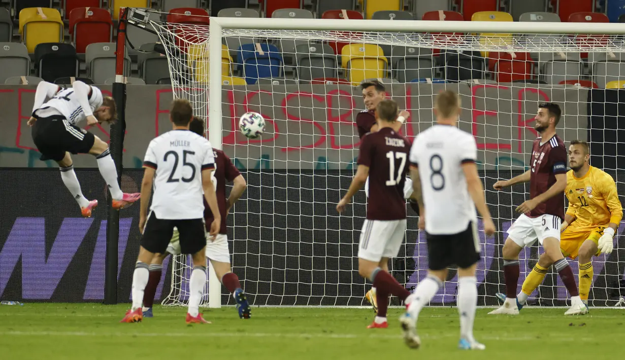 Penyerang timnas Jerman, Timo Werner (kiri) menyundul bola untuk melakukan percobaan gol ke gawang Latvia dalam laga uji coba jelang EURO 2020 di Merkur Spiel Arena, Selasa (8/6/2021) dini hari WIB. Timnas Jerman memenangkan pertandingan dengan skor 7-1 atas timnas Latvia. (Odd ANDERSEN / AFP)