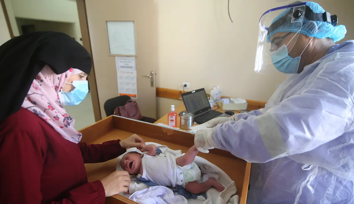 Seorang petugas medis yang mengenakan alat pelindung diri memeriksa seorang bayi di sebuah pusat layanan kesehatan saat pemberlakuan lockdown di Kota Rafah, Jalur Gaza, 9 September 2020. (Xinhua/Khaled Omar)