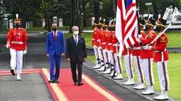 Presiden Indonesia Joko Widodo (kedua kiri) berjalan dengan Perdana Menteri Malaysia Muhyiddin Yassin saat mereka memeriksa penjaga kehormatan dalam pertemuan di Istana Merdeka, Jakarta, Jumat (5/2/2021). Muhyiddin Yasin tiba sekira pukul 10.30 WIB. (Agus Suparto, Indonesian President Palace via AP)