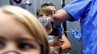 Finn Washburn (9) disuntik vaksin COVID-19 Pfizer-BioNTech saat adiknya, Piper Washburn (6) menunggu giliran saat vaksinasi anak 5 - 11 tahun di San Jose, California, Rabu (3/11/2021). Ini menjadi langkah perdana vaksinasi Covid-19 bagi anak kecil di Amerika Serikat. (AP Photo Noah Berger)