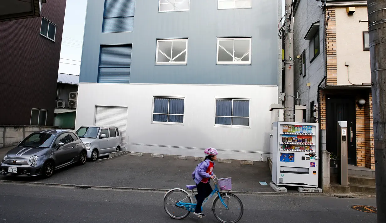 Seorang anak bersepeda di depan 'Corpse Hotel' di Kawasaki, Jepang, 20 April 2016. 'Hotel Mayat' ini dilengkapi dengan tabung pendingin otomatis dan juga disediakan dapur serta ruang tunggu bagi keluarga dan tamu yang datang melayat (REUTERS/Thomas Peter)