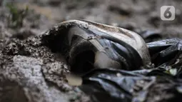 Sepatu tergeletak di salah satu rumah warga pascabanjir di kawasan Rawajati, Pancoran, Jakarta, Minggu (5/1/2020). Puluhan rumah warga yang berada di bantaran Kali Ciliwung itu mengalami kerusakan parah dan dipenuhi sampah serta lumpur akibat terjangan banjir. (merdeka.com/Iqbal Nugroho)