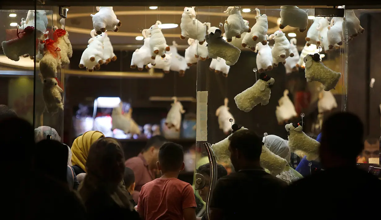 Keluarga Palestina membeli cokelat di sebuah toko yang dihiasi dengan boneka domba menjelang Hari Raya Idul Adha di kota Gaza pada Rabu (29/7/2020). (AP Photo/Hatem Moussa)