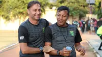 Dua asisten pelatih Persebaya Surabaya, Wolfgang Pikal dan Bejo Sugiantoro, bersenda gurau setelah latihan Persebaya untuk menghindari momen menjawab pertanyaan dari awak media. (Bola.com/Aditya Wany)