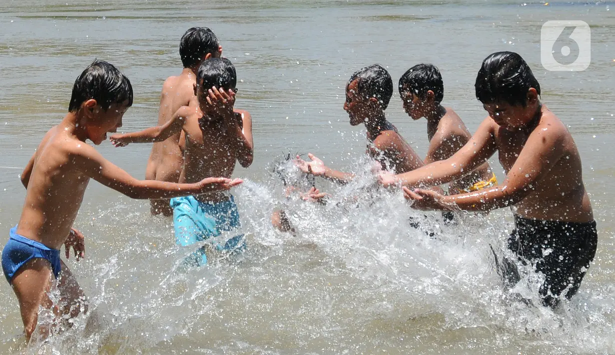 Anak-anak bermain pada aliran Sungai Cisadane di kawasan Keranggan, Setu, Tangerang Selatan, Banten, Minggu (20/3/2022). Cuaca panas terik dimanfaatkan mereka untuk berendam sambil bermain. (merdeka.com/Arie Basuki)
