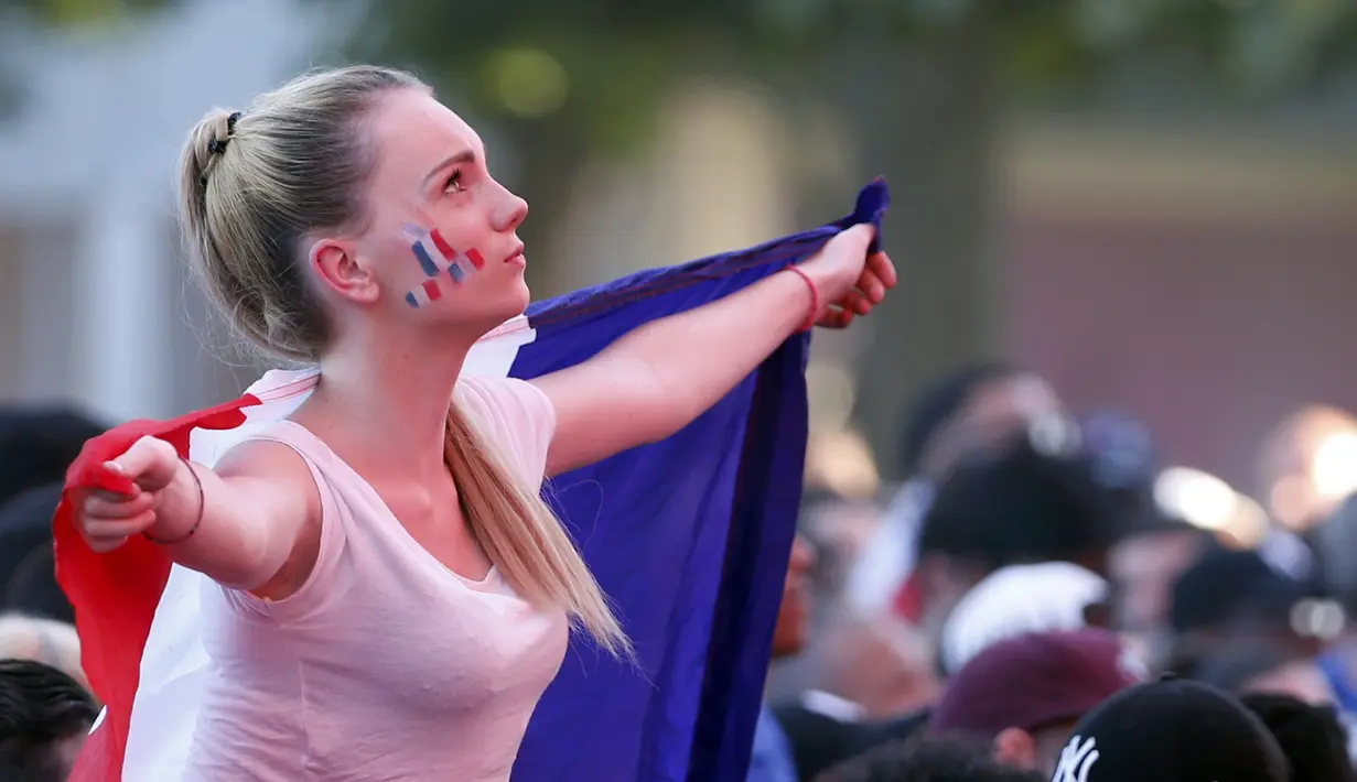 Aksi fans cantik Prancis dengan membentangkan bendera diareal fan zone saat timnya melawan Jerman pada semifinal piala Eropa 2016 di Paris, (7/7/2016). (REUTERS/Regis Duvignau)