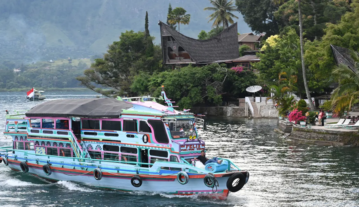 <p>Gambar pada 3 April 2019 menunjukkan sebuah kapal wisata tiba di Pulau Samosir, pulau vulkanik di tengah Danau Toba, provinsi Sumatera Utara, 3 April 2019. Di kalangan masyarakat Batak sendiri, Danau Toba ibaratnya inang atau ibu yang akan selalu menanti dengan keindahannya. (GOH CHAI HIN / AFP)</p>