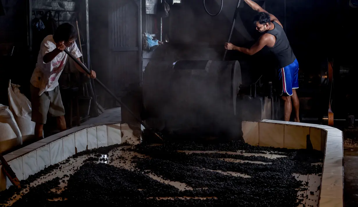 Para pekerja menyebarkan biji kopi robusta setelah disangrai secara tradisional di sebuah pabrik biji kopi kecil di Banda Aceh (14/11/2020). (AFP/Chaideer Mahyuddin)