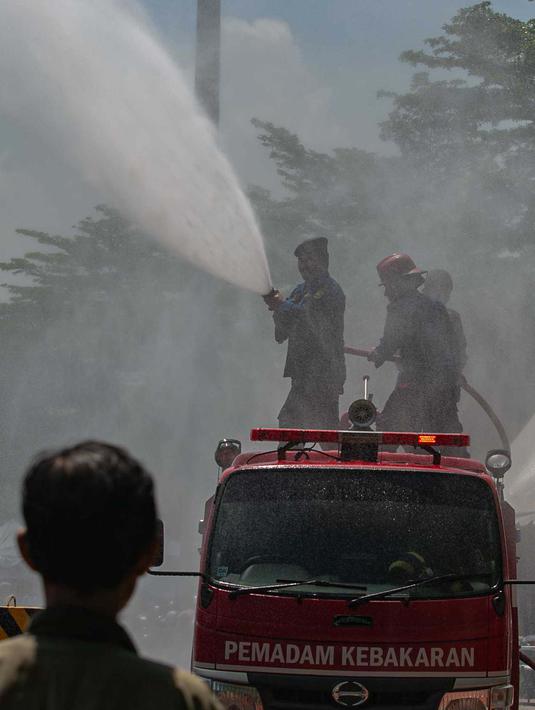 Pendinginan dilakukan menyemprot lokasi sekitar dan bagian atas tenda antrean motor pemudik. (Liputan6.com/Angga Yuniar)