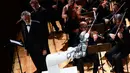 Robot YuMi saat tampil untuk pertama kalinya dalam konser Lucca Philharmonic Orchestra bersama Flutist Italia Andrea Griminelli (kedua kiri) dan penyanyi tenor Italia Andrea Bocelli di The Teatro Verdi di Pisa, Italia (12/9). (AFP Photo/Miguel Medina)