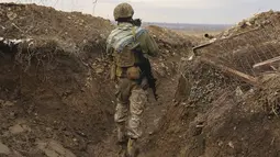 Tentara Ukraina memegang kucing dan berjalan di parit di garis pemisah dari pemberontak pro-Rusia dekat Debaltsevo, wilayah Donetsk, Ukraina, Jumat (3/12/2021). Ukraina mengklaim Rusia telah mengirim lebih dari 94 ribu personel ke perbatasan. (AP Photo/Andriy Dubchak)