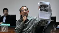 Suryadharma Ali (SDA) menunjukkan sebuah koran saat menjalani sidang pembacaan dakwaan di Pengadilan Tipikor, Jakarta, Senin (31/8/2015). SDA didakwa telah menggunakan Dana Operasional Menteri (DOM) hingga Rp1,821 miliar. (Liputan6.com/Herman Zakharia)