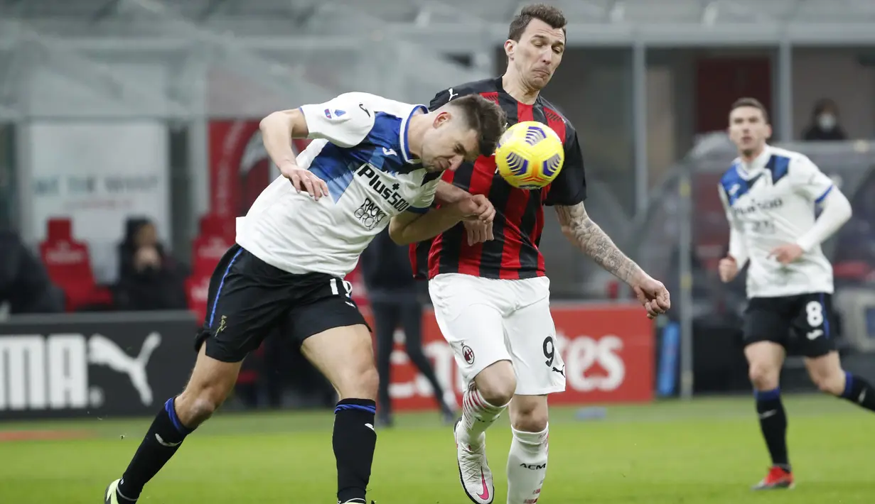 Penyerang AC Milan, Mario Mandzukic berebut bola dengan bek Atalanta, Berat Djimsiti pada pertandingan lanjutan Liga Serie A Italia di Stadion San Siro, Minggu (24/1/2021). Meski kalah, hasil Liga Italia ini tetap membuat AC Milan berada di puncak klasemen. (AP Photo/Antonio Calanni)