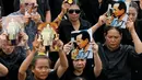 Sejumlah pelayat memegang foto Raja Bhumibol Adulyadej saat berkumpul di luar Grand Palace sambil menyanyikan rekaman lagu kerajaan, di Bangkok, Thailand, (22/10). Raja Bhumibol meninggal pada 13 Oktober di usia 88. (REUTERS/Jorge Silva)