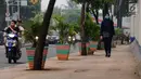 Warga melintasi pedestrian di Jalan TB Simatupang, Jakarta, Jumat (7/7). Pedestrian di Jalan TB Simatupang sekitar perempatan Pasar Rebo menjadi berwarna dengan tampilan pot cat warna warni. (Liputan6.com/Helmi Fithriansyah)