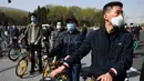 Orang-orang berdiri di sebuah jalan dekat Lapangan Tiananmen selama peringatan nasional tiga menit untuk memperingati orang-orang yang meninggal dalam wabah coronavirus COVID-19, di Beijing (4/4/2020). (AFP/Greg Baker)